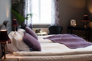Sovrum med lila kuddar och överkast och lampor med toffsar