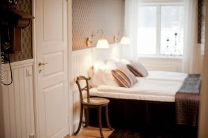 Rum med bruna tapeter och brunrandiga kuddar och överkast