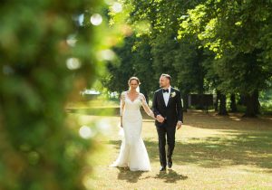 Brudpar som går hand i hand på gräsmattan